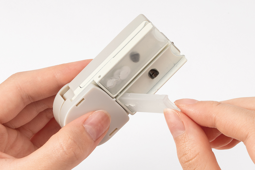 パンチ裏面のダストケースの蓋を開き、パンチ屑を捨てている様子。