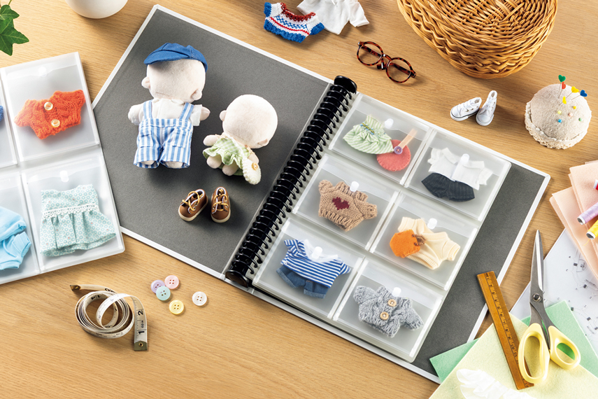 『バインダー』の使用例の画像。中のポケットは「＜ポッケde整理（なんでもポケット）＞　A4判 6ポケット（NP-56M）」で、小さいぬいぐるみの洋服が収納されている。