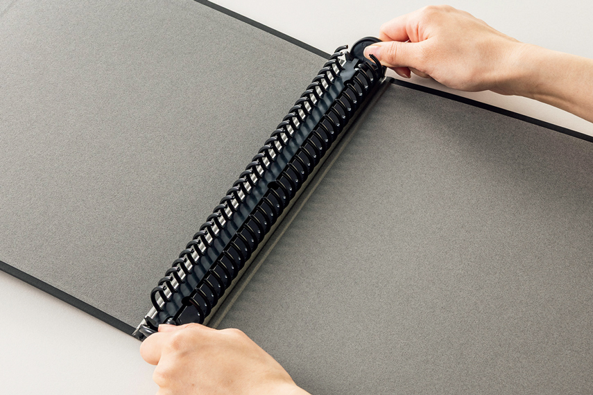 樹脂製のロック式リングとじ具を開けている様子の画像。