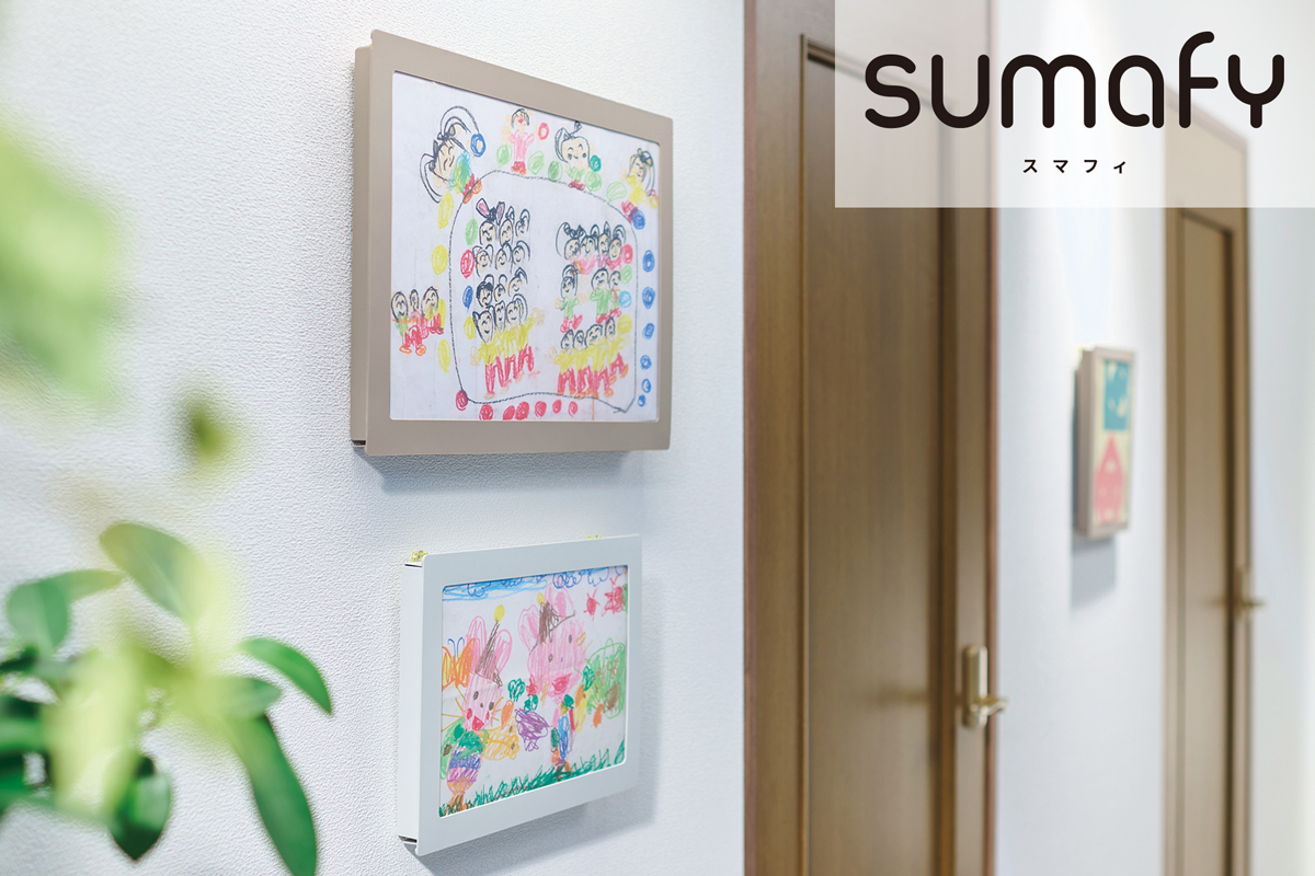 ＜スマフィ＞フレームホルダーのイメージ画像。自宅をイメージした場所の壁に、フレームホルダーが2つ縦に並んで掛けられている。上段に掛かっているのはA3判（ベージュ）、下段はA4判（ライトグレー）。