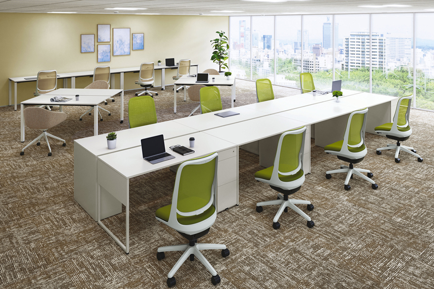 オフィス内をイメージした場所に、「片袖机」が横並びで4台ずつ・向かい合わせに並べて島型レイアウトに配置した画像。カラーは、天板：ホワイト、本体：ホワイト。
